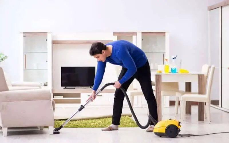 man vacuuming under furniture