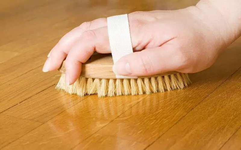 scrubbing wood floor with brush