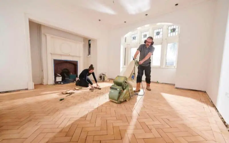 man and woman sanding wood floor