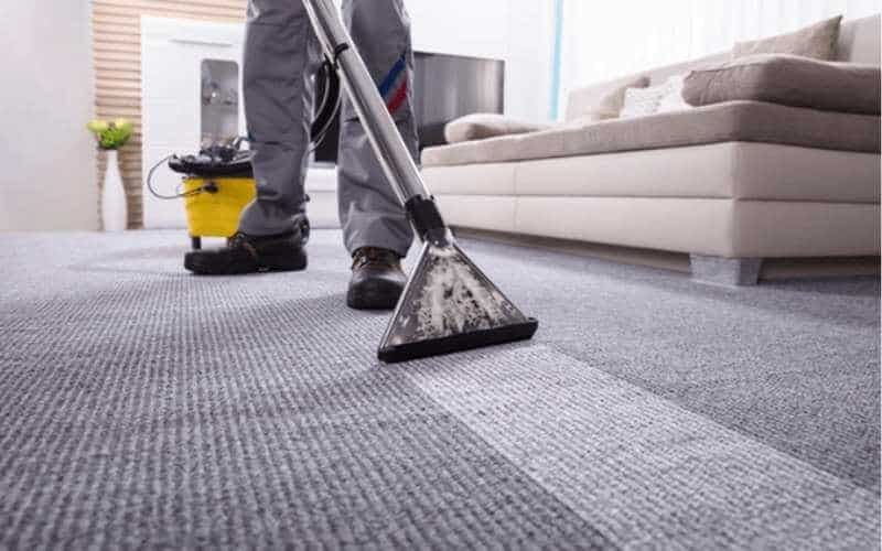 man cleaning carpet with shop vac